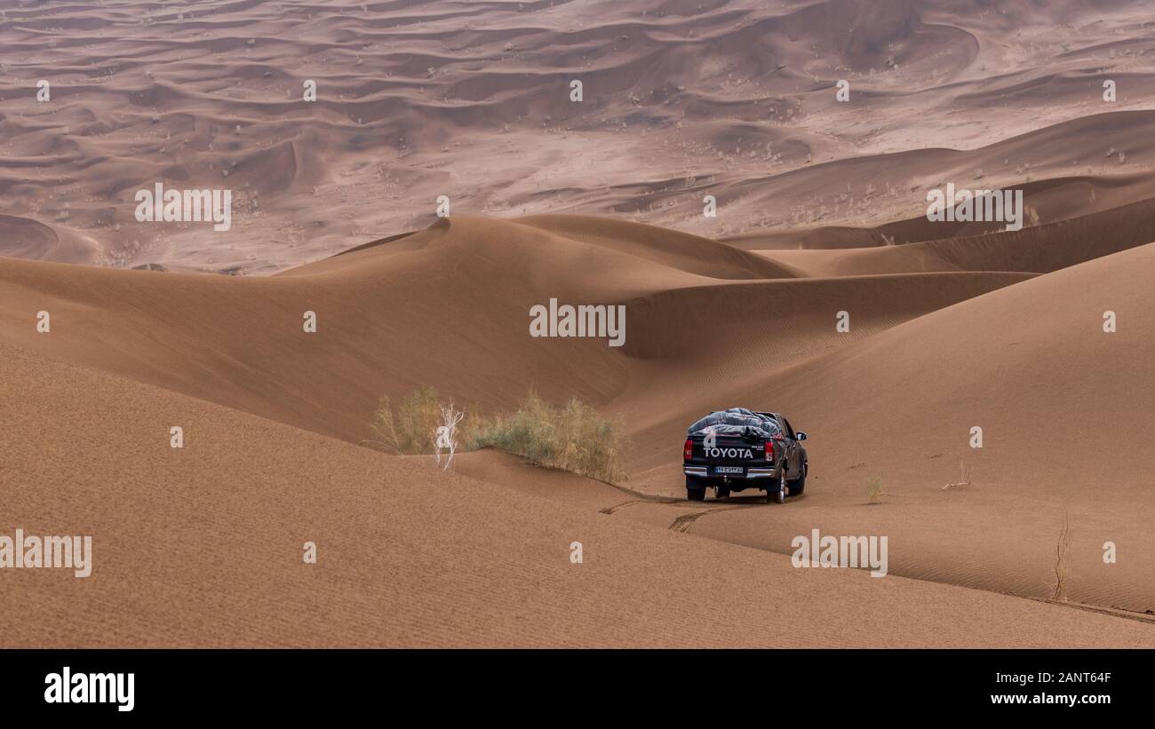 toyota hulux revo klettert bei regnerischem Wetter in der Dasht e lut- oder sahara-Wüste eine Sanddüne hinab Stockfoto