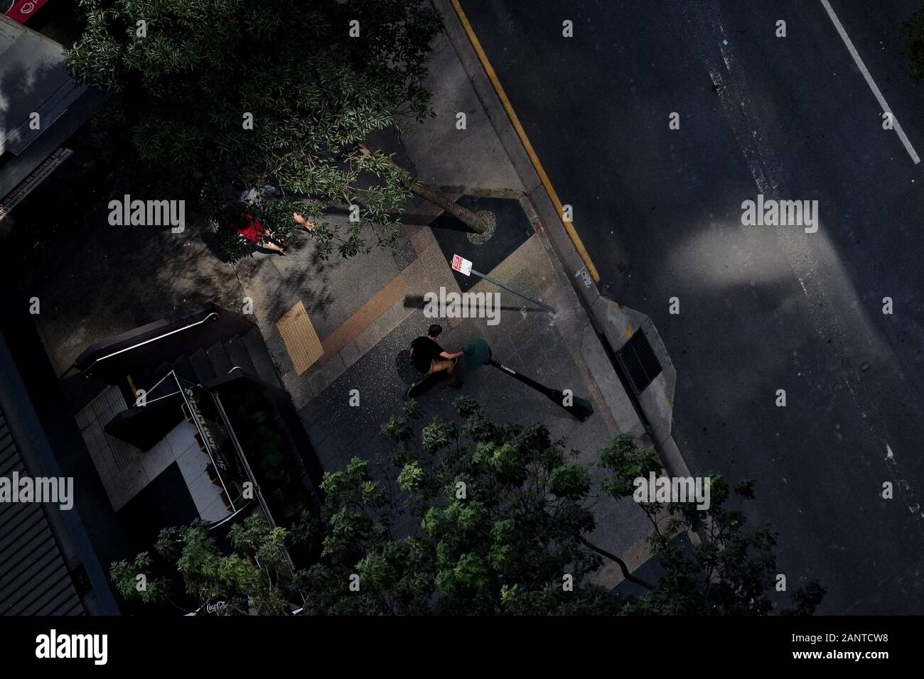 Skateboarder macht Tricks in der Albert Street brisbane von der 26. Etage über, oben nach unten, Draufsicht, reflektiertes Licht auf der Straße und Bäume darunter Stockfoto