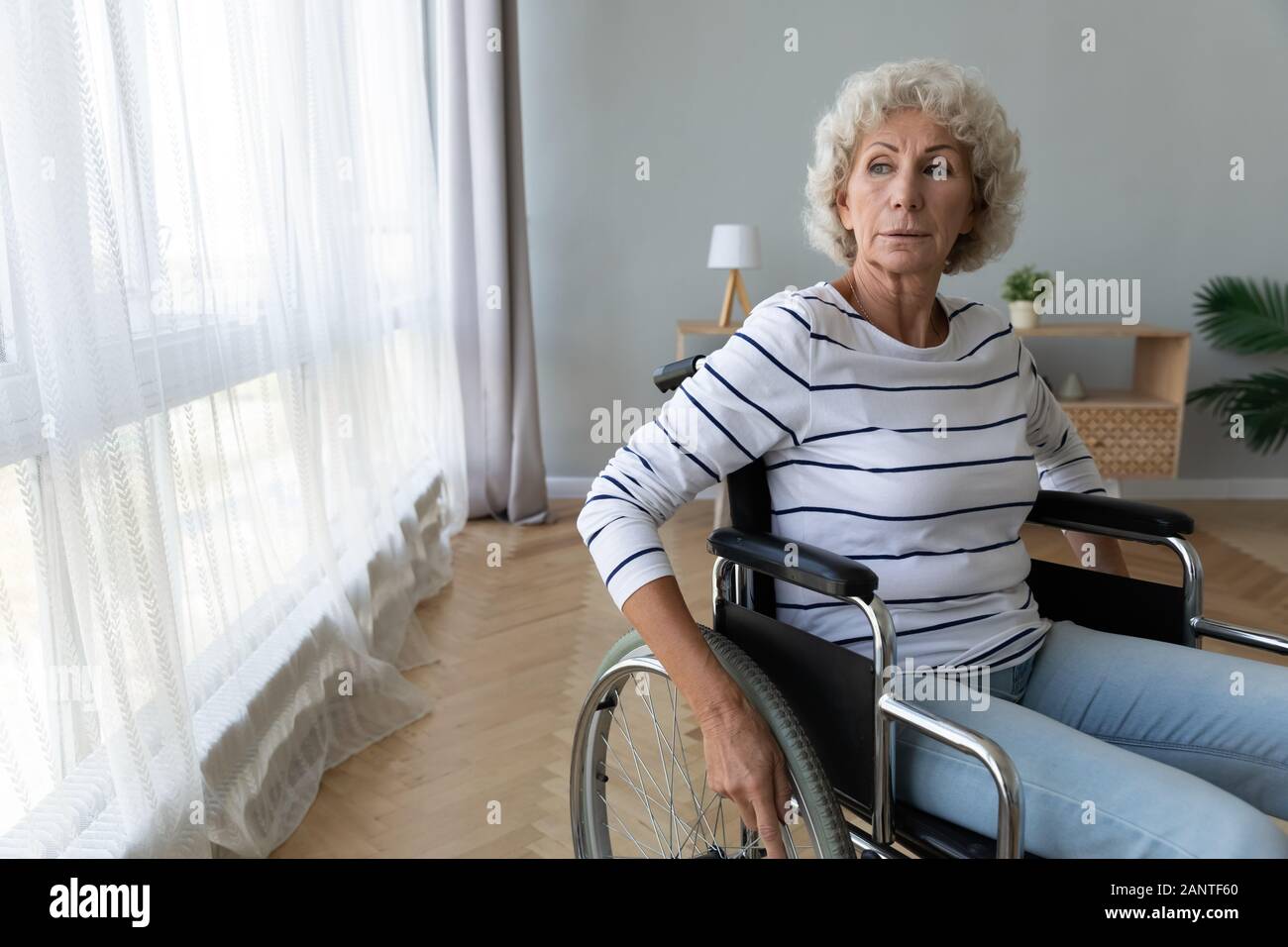 Nachdenklich ältere Frau sitzt im Rollstuhl, halten sich an den Händen auf Rädern Stockfoto