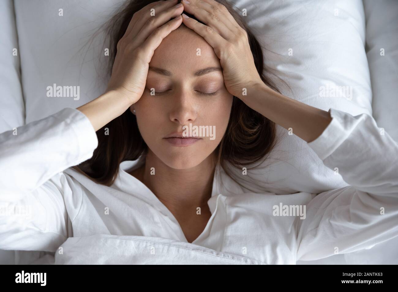 Ansicht von oben gedrückt Frau leidet unter Kopfschmerzen, im Bett liegend Stockfoto