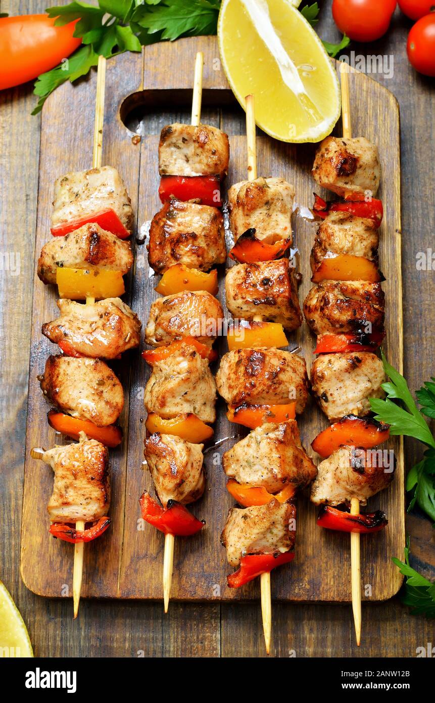 Fried Chicken Döner auf einem Schneidebrett und frischem Gemüse auf hölzernen Tisch. Ansicht von oben, flach Stockfoto