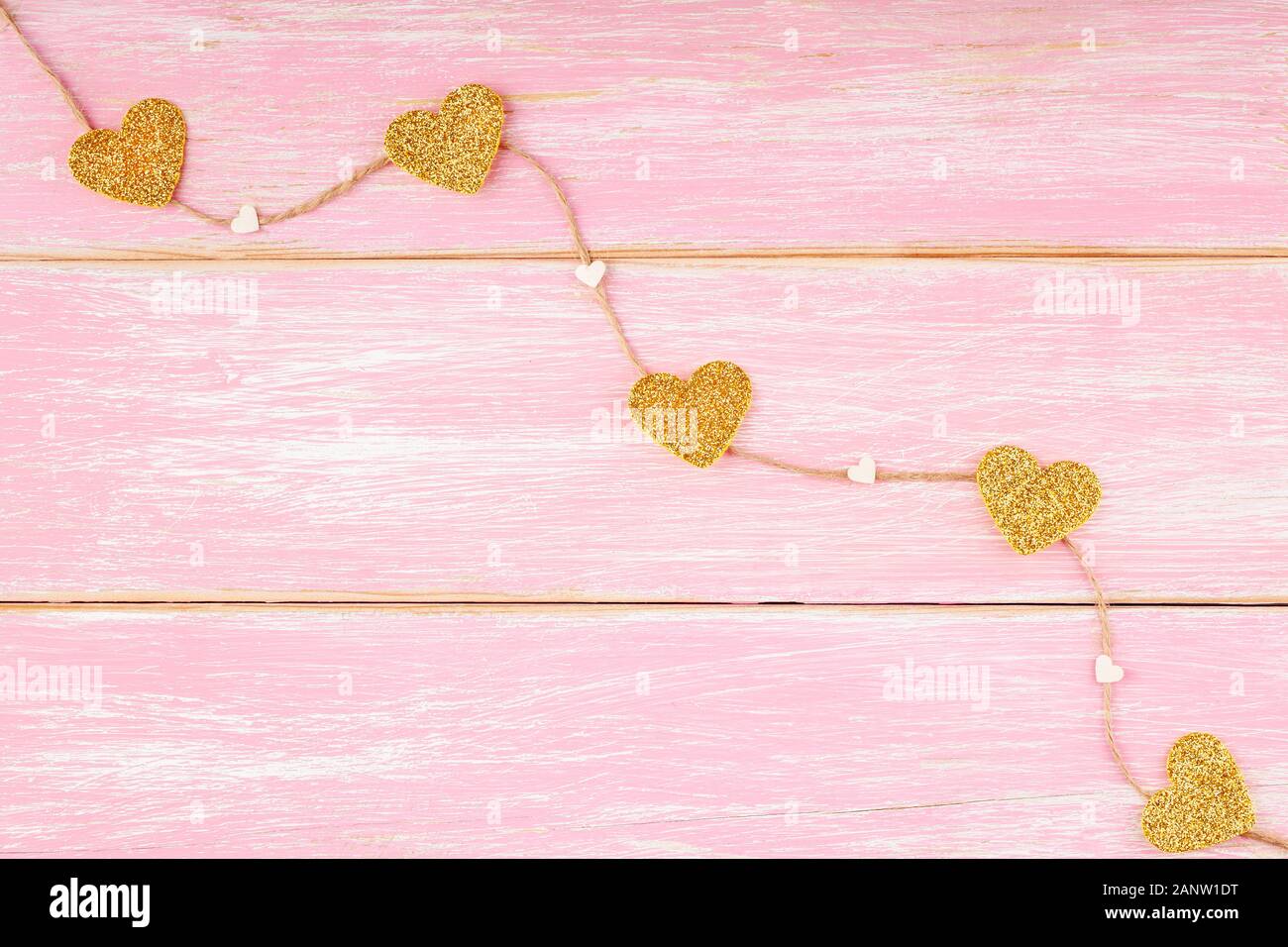 Jute Seil mit Gold Glitzer Herzen und Konfetti Herzen auf rosa Hintergrund Stockfoto