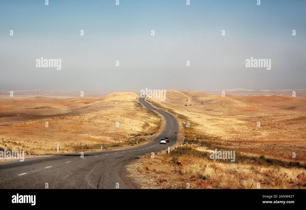 Autos fahren auf Wüste Straße durch Steppe und Hügel in Kasachstan Stockfoto