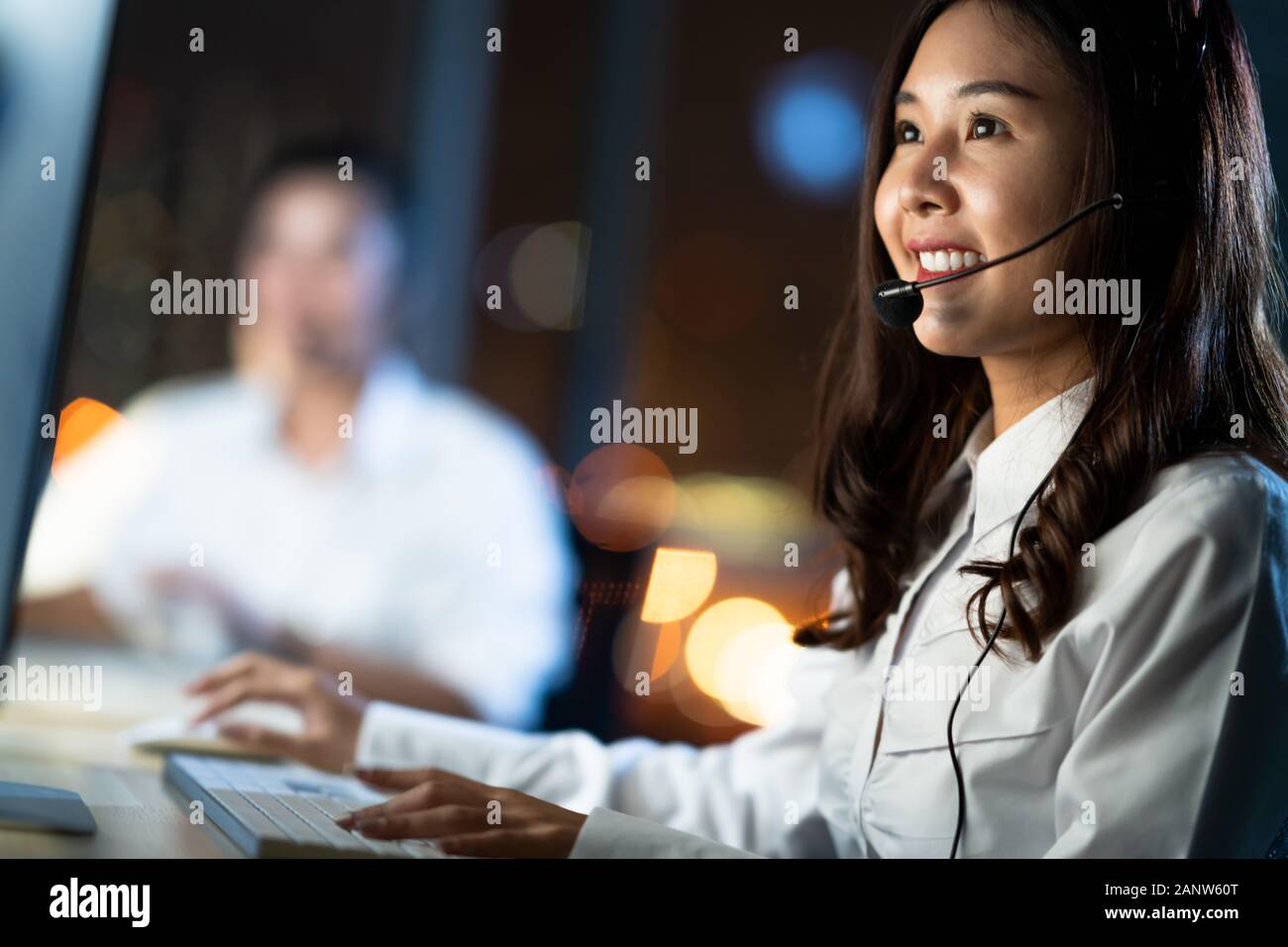 Asian Woman arbeitet als Kundendienst-Telefonanbieter oder Callcenter-Telefonanbieter mit Desktop-Computer und Mikrofonkopfhörer, spätabends verschoben Stockfoto