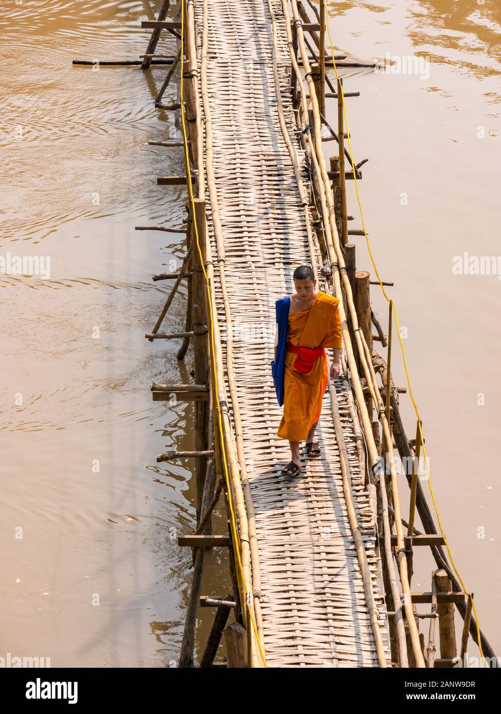 Buddhistischer Mönch im orangen Gewand Kreuzung bamboo Brücke, Fluss Nam Khan, Luang Prabang, Laos, Südostasien Stockfoto