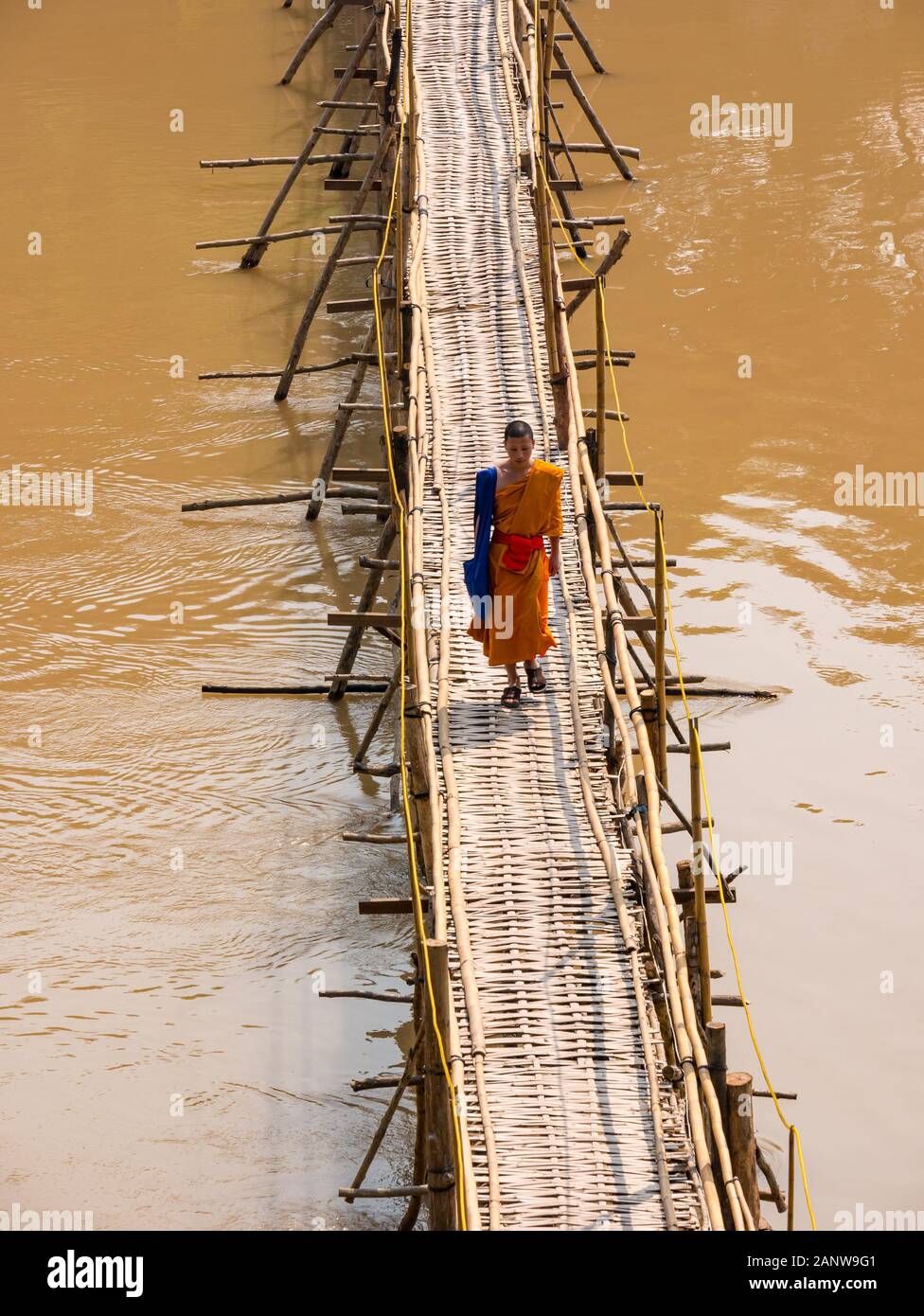 Buddhistischer Mönch im orangen Gewand Kreuzung bamboo Brücke, Fluss Nam Khan, Luang Prabang, Laos, Südostasien Stockfoto