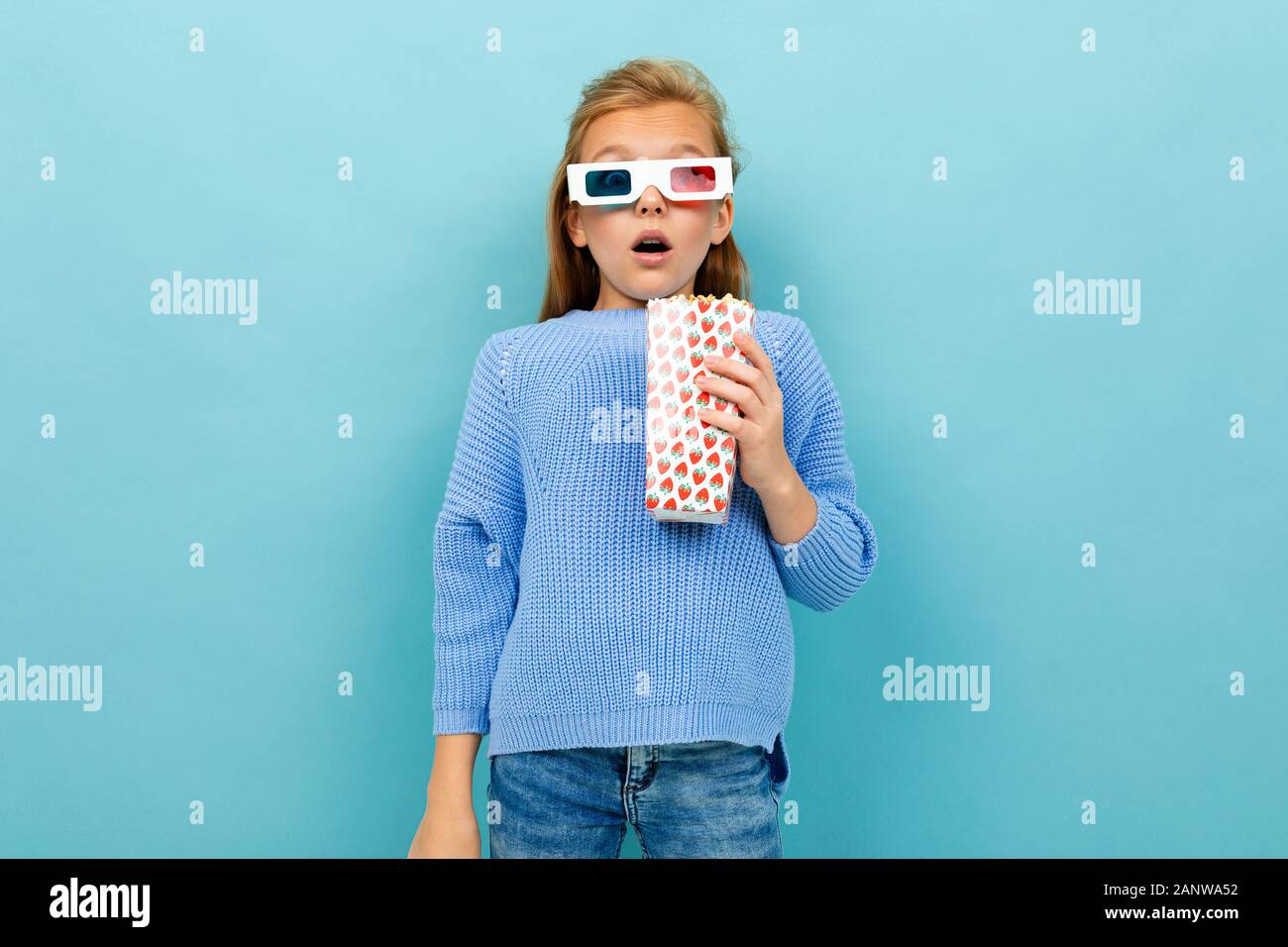 Ein Mädchen mit Make-up und langen braunen Haaren, 3D-Brille sieht Film oder Cartoon mit Popcorn aus Stockfoto