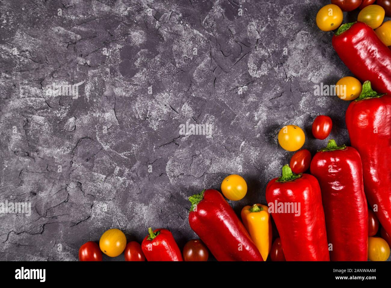 Chili geformten roten Paprikaschoten Paprikaschoten und kleine gelbe und rote Tomaten Gemüse auf dunklem Hintergrund mit Kopie Raum Stockfoto