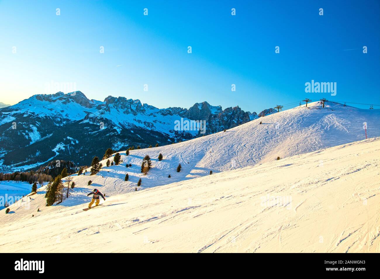 Winterlandschaft in den Bergen der Alpen, Italien, Skipiste mit Snowboarder im Fassatal mit Bergkette im Hintergrund, Region Vigo di Fassa Stockfoto