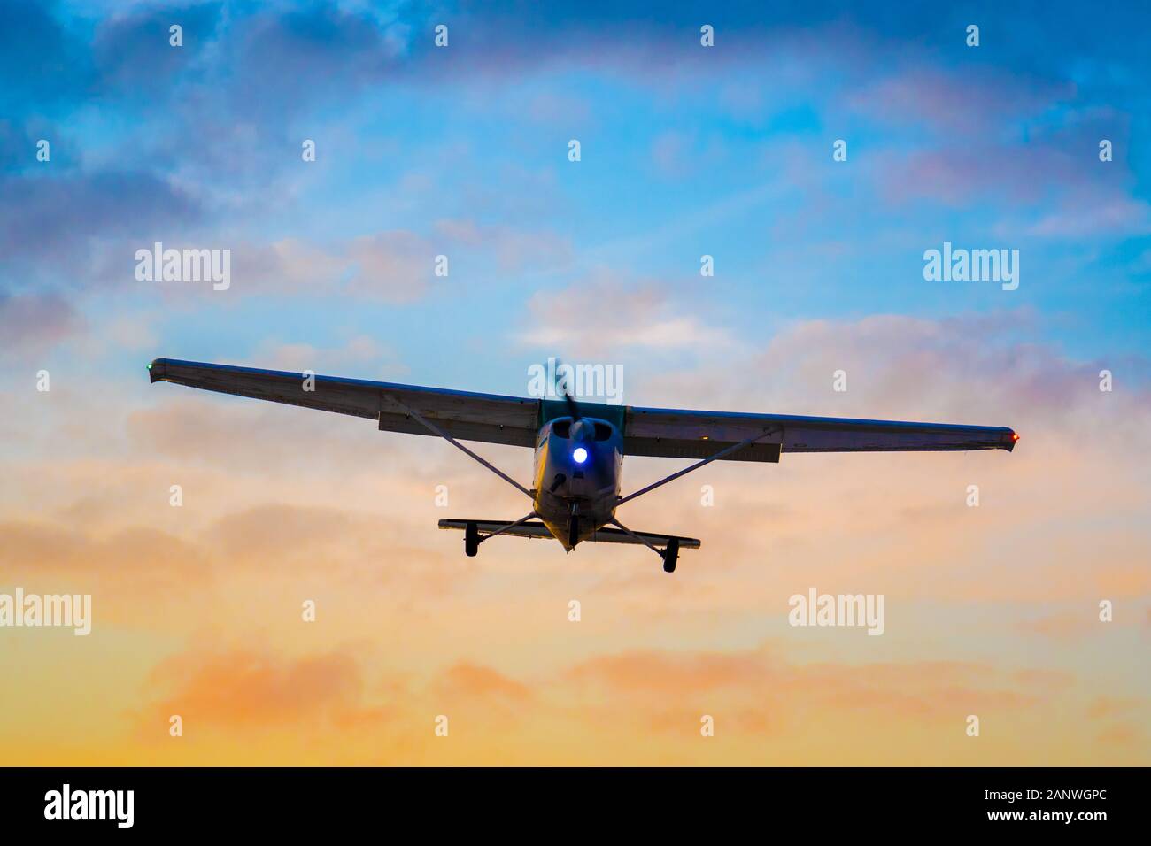 Schuß eines silhouetted, nicht identifizierbare privaten Flugzeuge im Endanflug für die Landung als die Sonne untergeht. Stockfoto