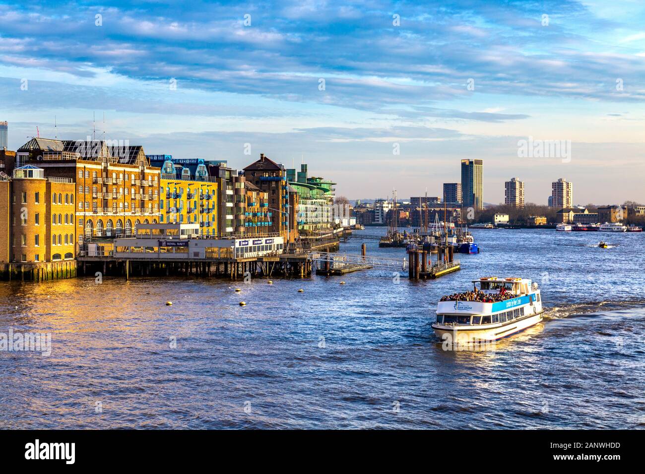 Am Ufer der Themse, von der Tower Bridge aus gesehen, mit Blick nach Osten in Richtung St Katherine's and Wapping, London Eye River Cruise Boat voller Touristen, London, Großbritannien Stockfoto