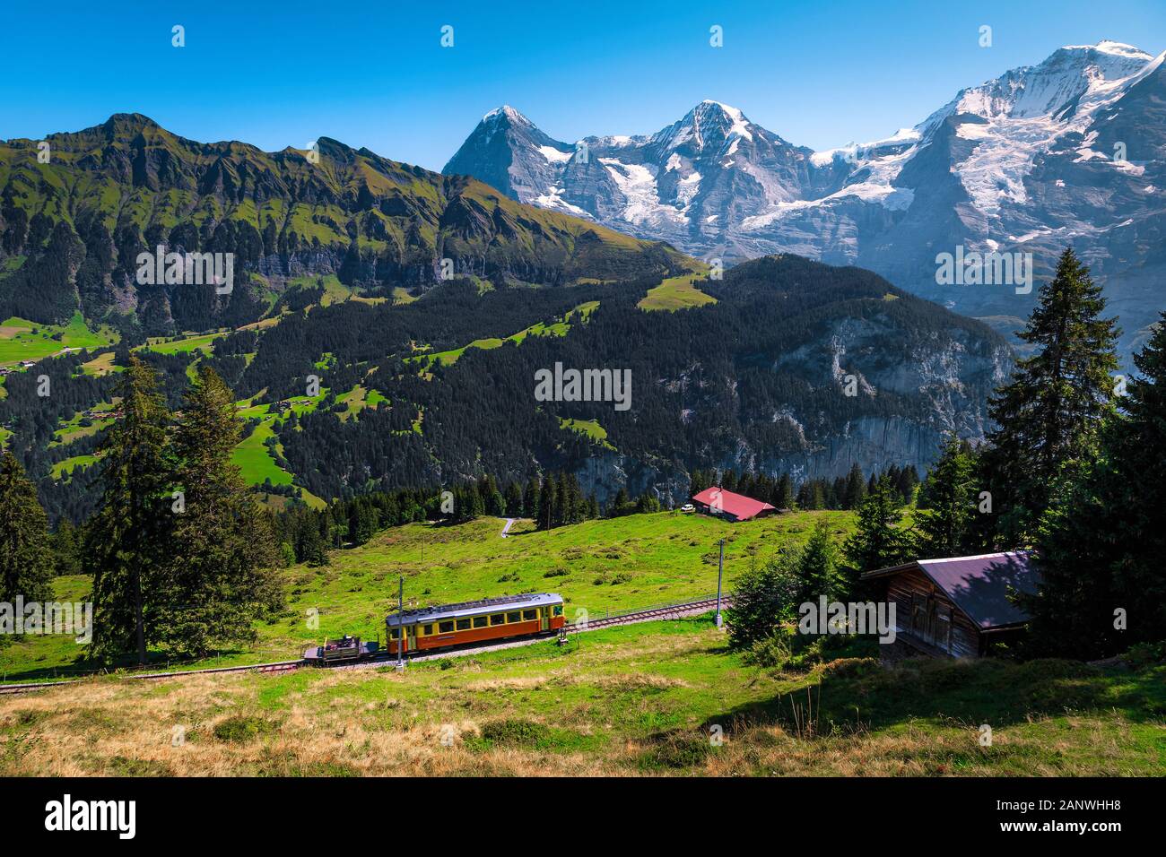 Unvergesslichen Sommer reisen, beliebte Elektrische rote Bummelzug mit hohen Verschneiten Schweizer Bergen im Hintergrund, in der Nähe von Mürren Bergstation Stockfoto