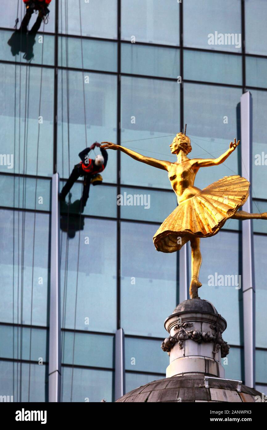 Statue der Russischen ballerina Anna Pavlova oben auf der Kuppel des Victoria Palace Theatre und die Arbeiter auf Gebäude mit Glasfront, Victoria, London, Großbritannien Stockfoto