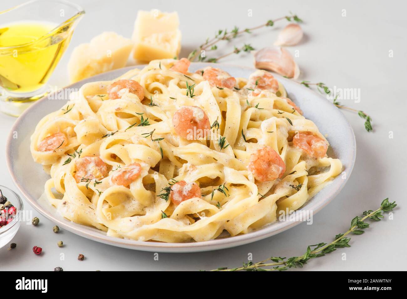 Italienische Pasta Fettuccine oder Tagliatelle in eine cremige Soße mit Garnelen in eine Platte auf weißem Marmor tisch. Nach oben Schließen Stockfoto