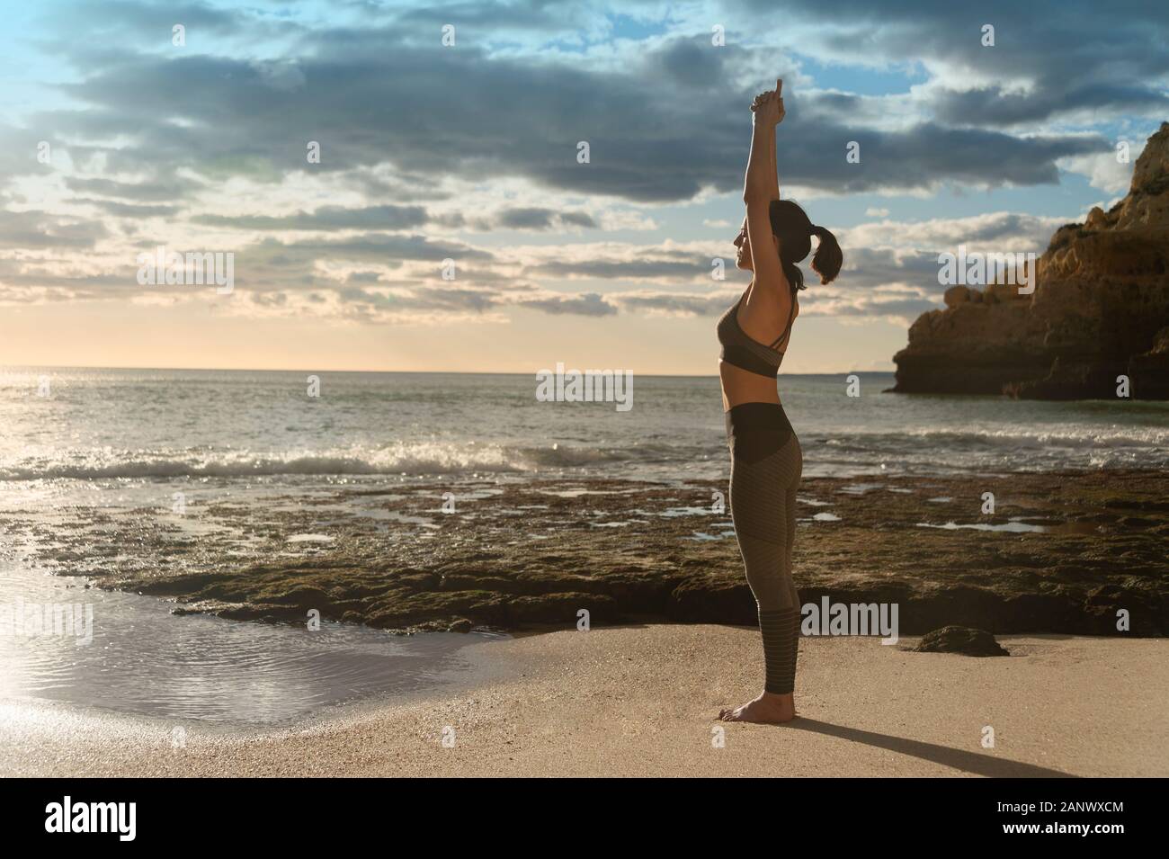 Passende Frau, stehend auf einem Strand in der Sonne Yoga und Meditation Stockfoto