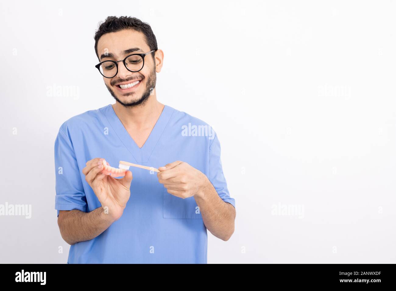 Junge Zahnarzt in Uniform falsche Zähne putzen mit der Zahnbürste in der Isolation Stockfoto