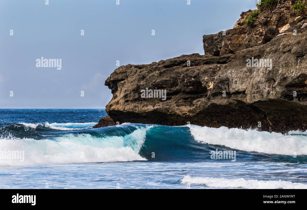 Wellen an geheimen Strand, Nusa Ceningan, Bali, Indonsia. Felsigen Klippen im Hintergrund. Blue Sky in der Entfernung. Stockfoto