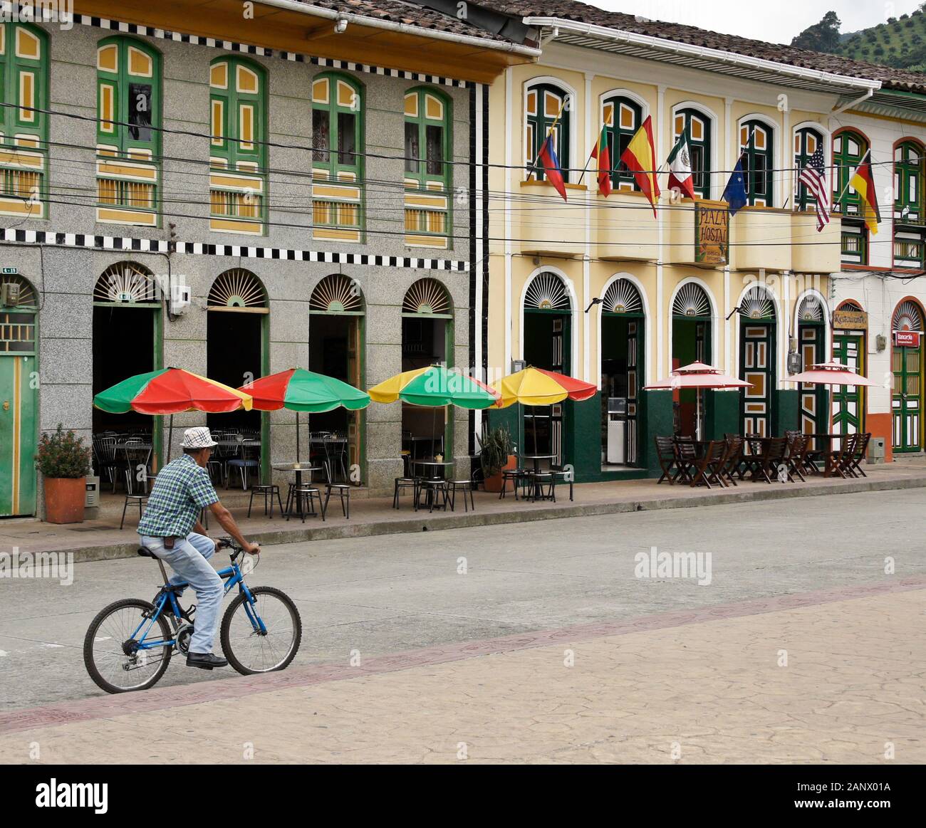 Mann auf dem Fahrrad reiten Vergangenheit farbenfrohe Gebäude mit Blick auf Main Plaza der Stadt (Plaza Principal), Pijao, Quindio Abteilung, Kolumbien Stockfoto