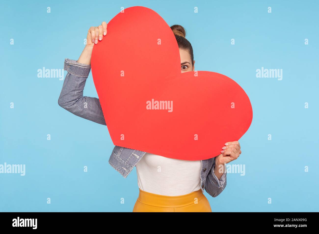 Portrait von lustigen optimistische Frau peeking aus großen roten Herz aus Papier in den Händen, Suchen mit neugierig und erstaunt, Big Eye, Überraschung am Valentinstag da Stockfoto