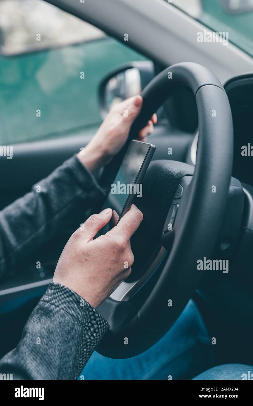 Texting und Fahren ist gefährlich Verhalten im Verkehr, in der Nähe der weiblichen Hand Eingeben von SMS auf Handy, während sie durch die Landschaft zu reisen Stockfoto