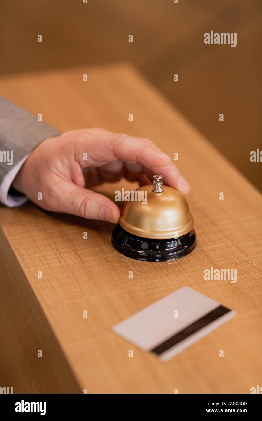 Hand der zeitgenössischen Geschäftsmann über Ring Taste auf hölzernen Rezeptionstresen Stockfoto