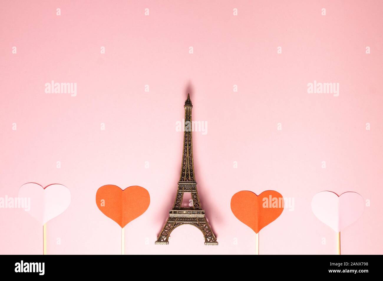 Der Eiffelturm, zwei Rote und zwei rosa Herzen auf Holzstäbchen auf rosa Hintergrund. Flach Blick von oben auf die wichtigsten Sehenswürdigkeiten von Paris. Romantik, Liebe, Val Stockfoto