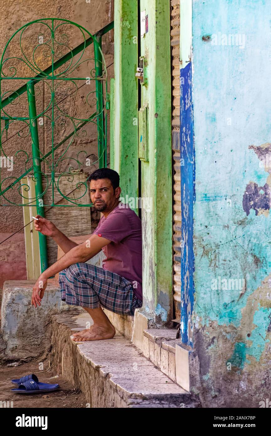 Landarbeiter, die eine Zigarettenpause vor der Tür eines Hauses auf der Insel Geziret Al Dahab in Kairo einlegen Stockfoto