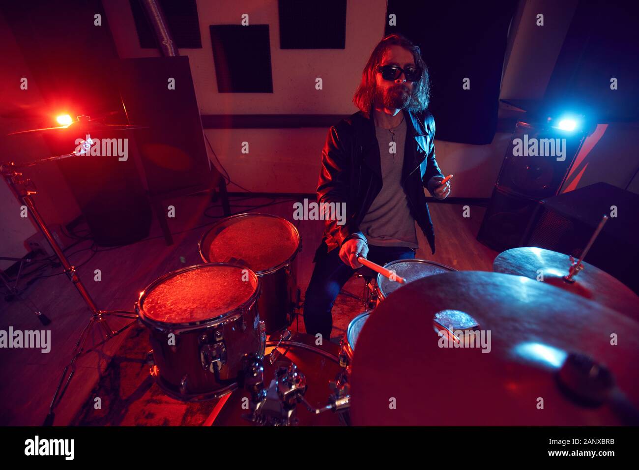 Hohen winkel Portrait von gutaussehenden jungen Mann rockigen Drums während Konzert in dunkel rot leuchten, Kopie Raum Stockfoto