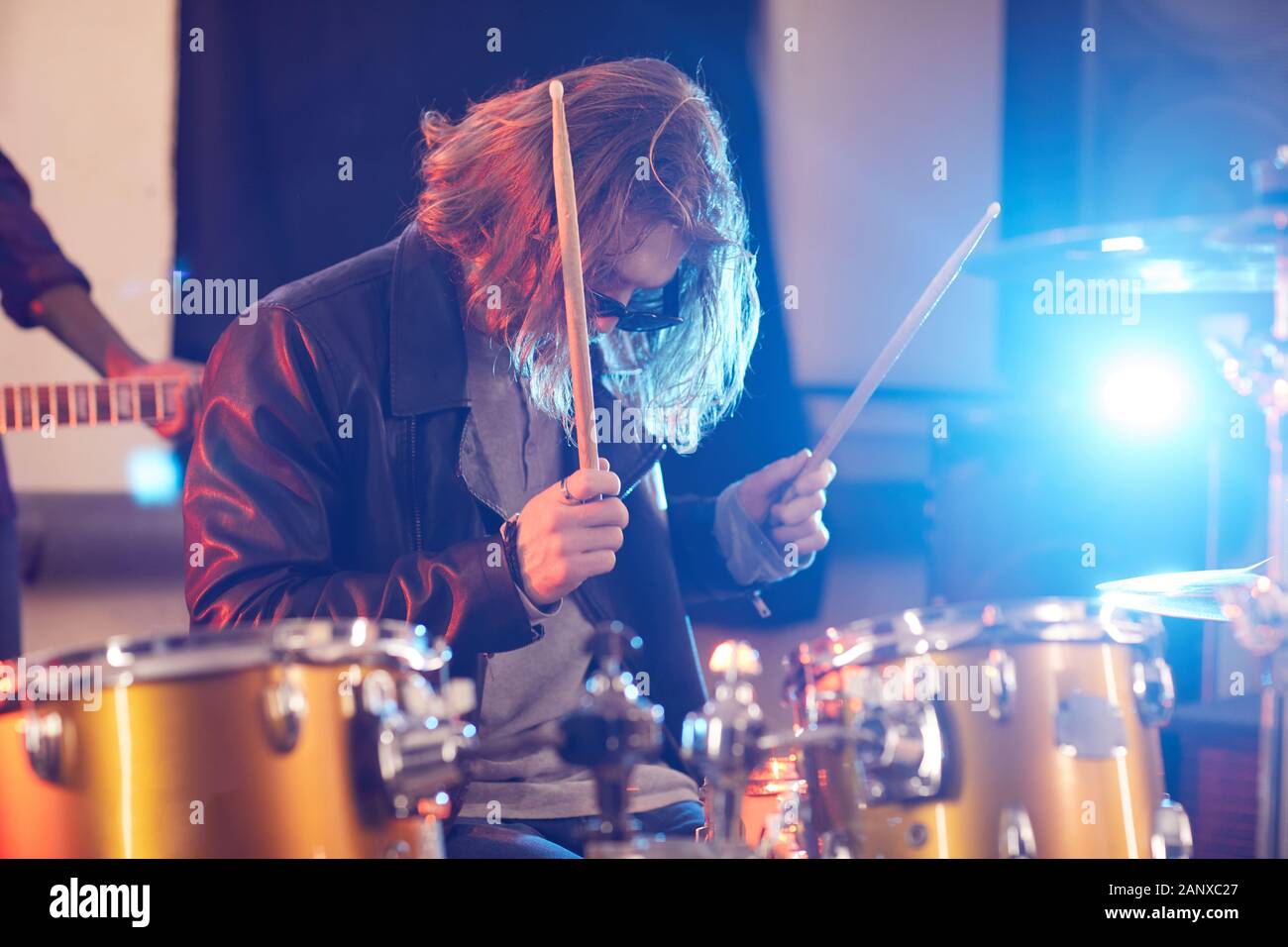 Seitenansicht Portrait von langhaarigen Mann rockigen Drums während Konzert in Spotlight, kopieren Raum Stockfoto