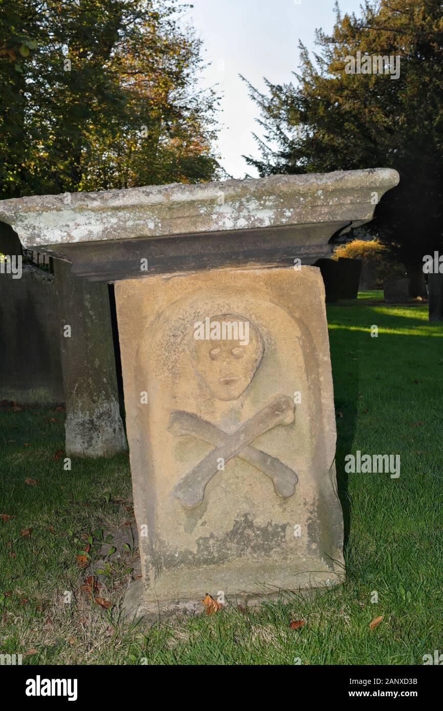 Schädel und Kreuzknochen am Ende des Grabes 7 in Eyam Village Churchyard, Derbyshire, England, Großbritannien, 17. Jahrhundert, Grad II. Gelistet Stockfoto