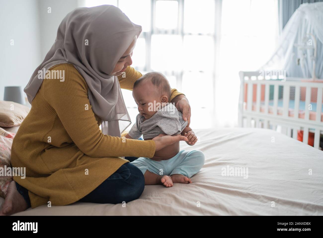 Asiatische muslimen wechseln ihre Kleidung für Babyjungen Stockfoto