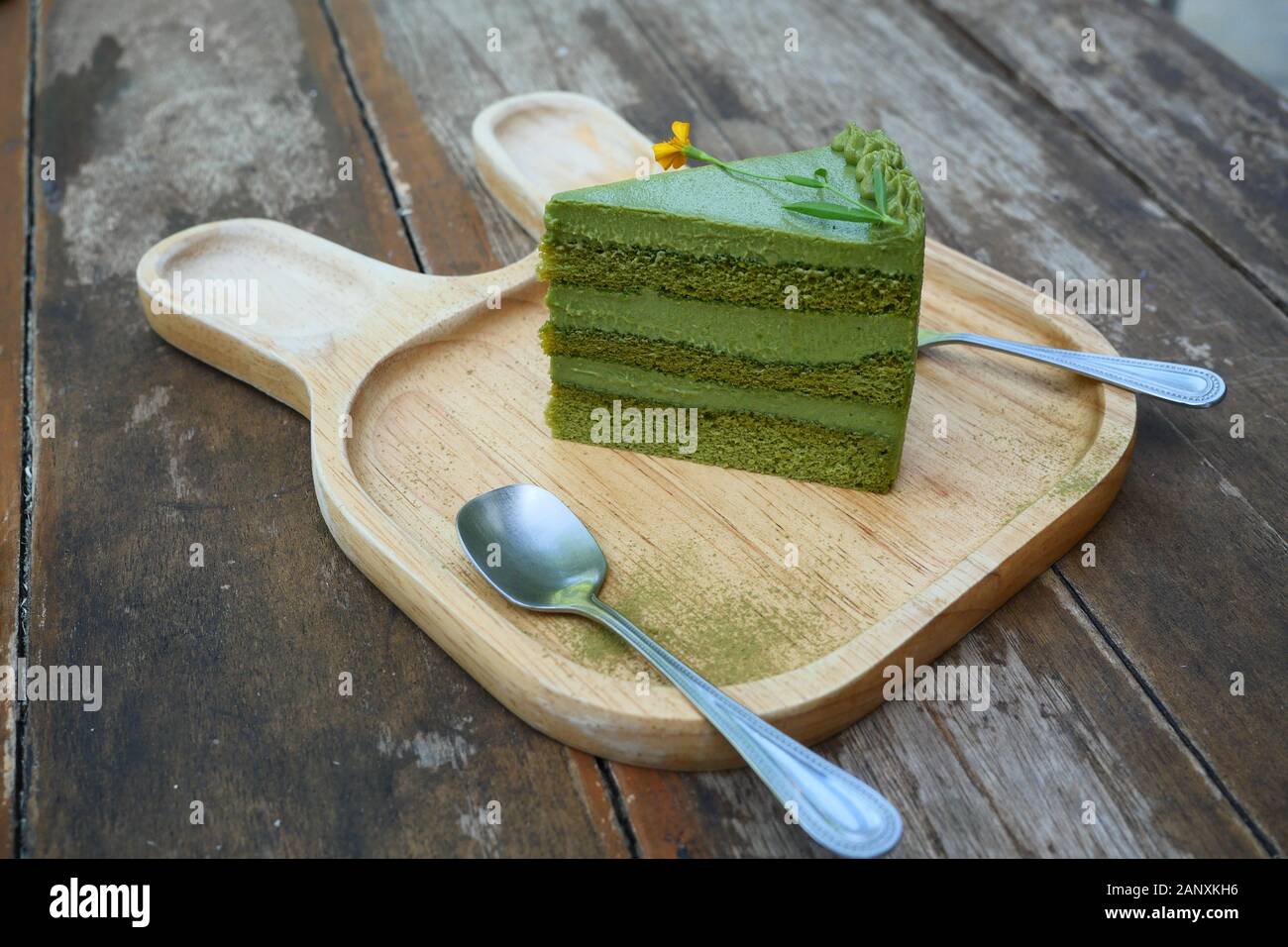 Japanische Matcha grüner Tee mit roten Bohnen Kuchen, süße Speisen mit Löffel und Gabel auf einer Holzplatte mit braunen Tisch im Hintergrund Stockfoto