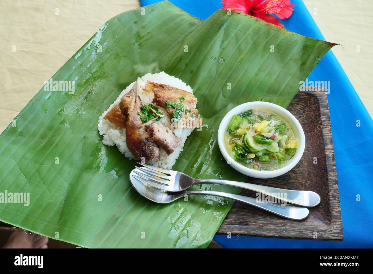 Reis garniert mit gegrilltem Hähnchen mit Löffel und Gabel auf Green Banana Leaf, Sauce aus Chili, Salz, Zitrone und Ananas in Weiß Gericht Stockfoto