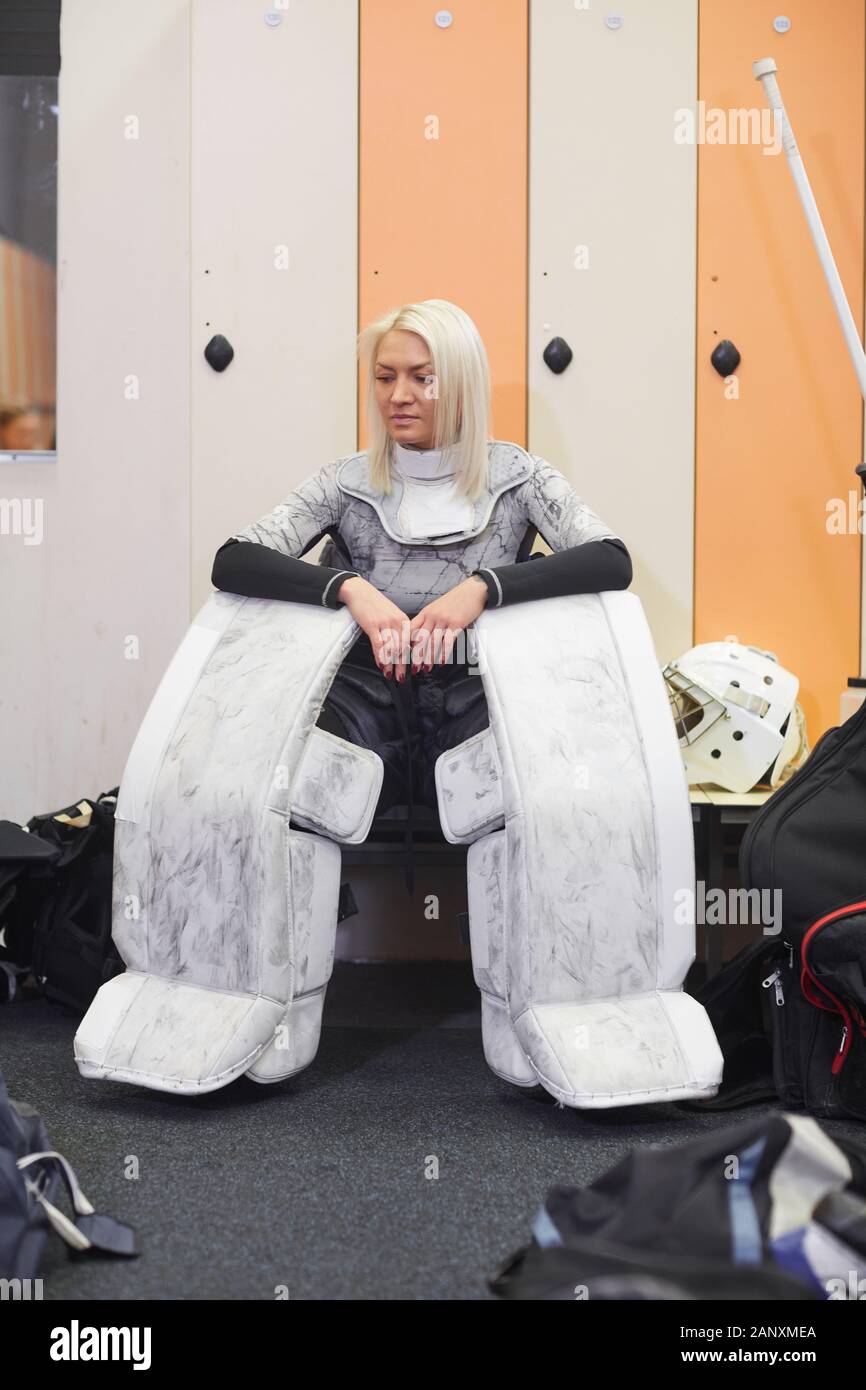 In voller Länge Porträt der sportliche junge Frau tragen volle hockey Gang sitzend auf Bank in der Umkleide, Kopie Raum Stockfoto