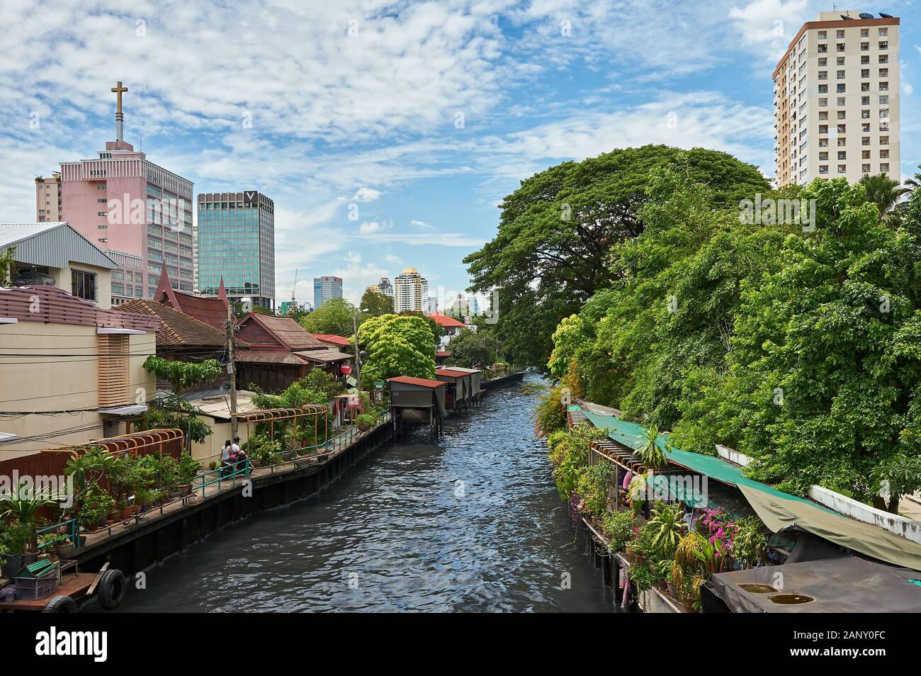 Bangkok, Thailand: idyllischer Blick eines khlong Wasserstraße in einer Nachbarschaft mit grünen Bäumen und Blumen, hohe Gebäude im Hintergrund Stockfoto