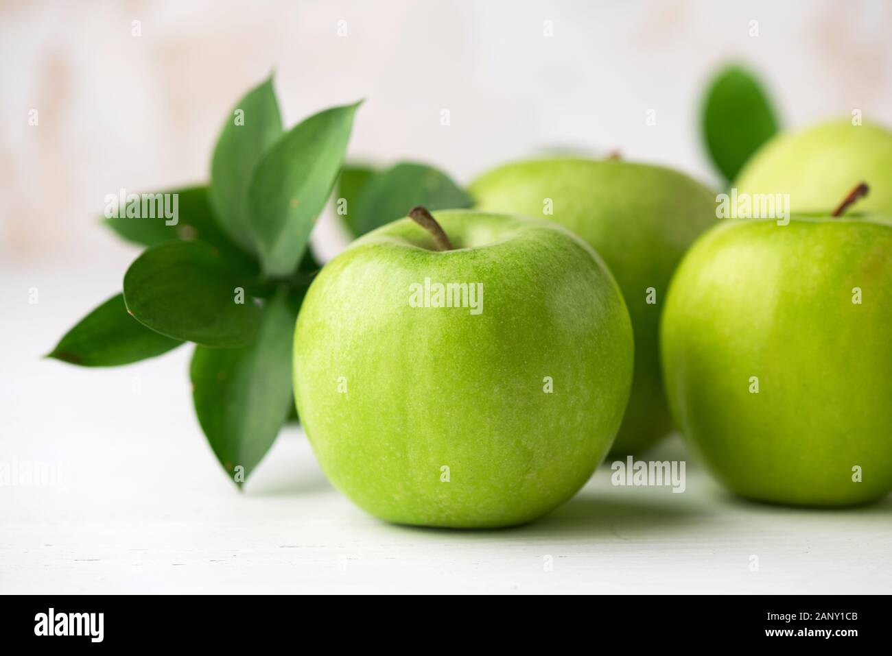 Grüne Äpfel mit grünen Blättern auf weißen Tisch Detailansicht. Gesunde knackig frische Früchte Stockfoto