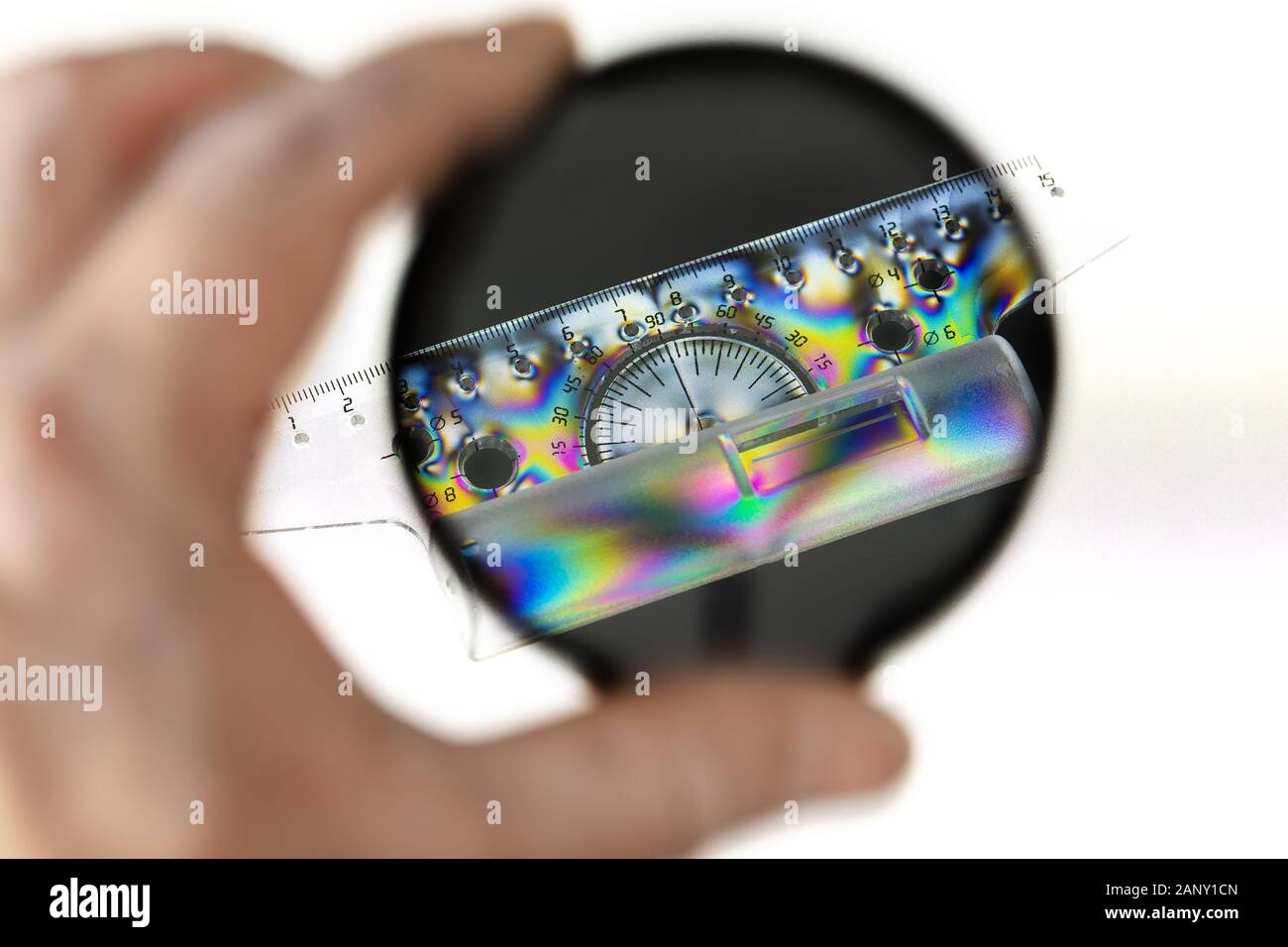 Transparenter Kunststoff Winkelmesser mit Lineal, durch einen Polarisationsfilter mit polarisierter Lichtquelle fotografiert. Stockfoto