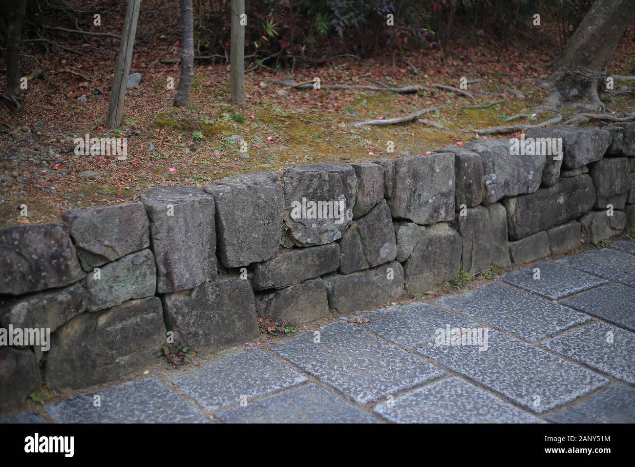Stein Stützmauer separate Grünfläche und grobem Granit Steinplatten Fußweg. Landschaft und Garten Design Details. Stockfoto