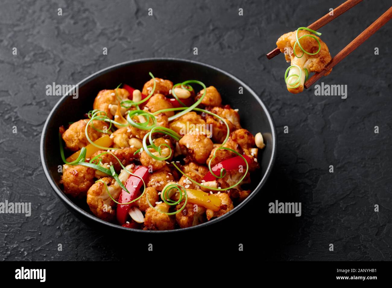 Kung Pao Blumenkohl an dunklen Schiefer Hintergrund. Sichuan Kung Pao Blumenkohl ist chinesische Küche vegetarisches Gericht mit Chili peppers, Erdnüsse, Saucen ein Stockfoto