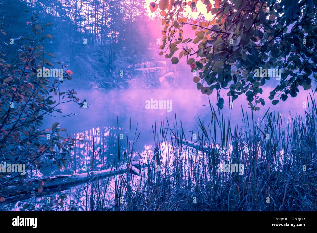 Nebeliger morgen früh. Sonnenaufgang über einem See mit einem felsigen Ufer. Ländliche Landschaft im Sommer Stockfoto