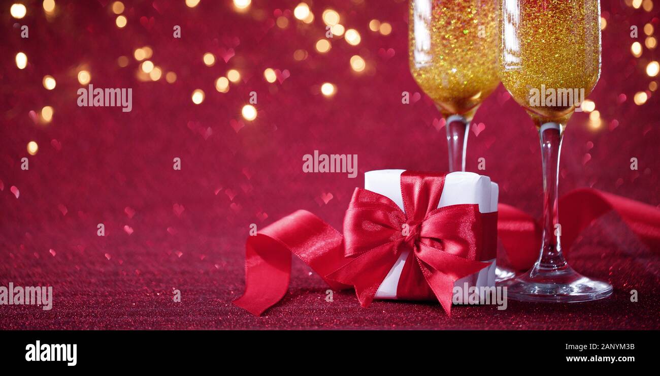 Zwei Gläser Champagner mit verpackte Geschenk lila Glitzer Hintergrund. Valentines Tag Konzept Stockfoto