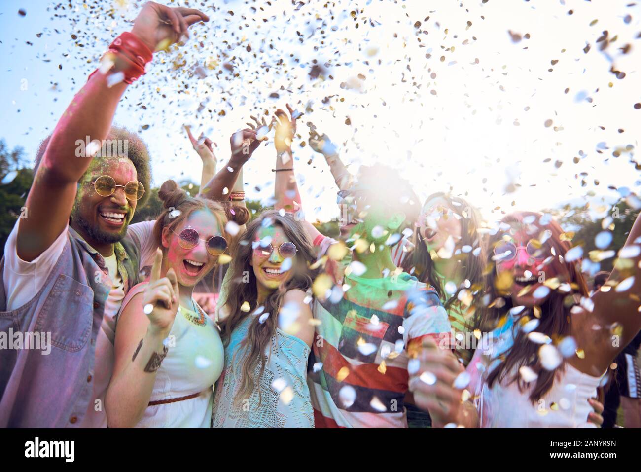 Freunde feiern Holi Festival unter Dusche Konfetti Stockfoto