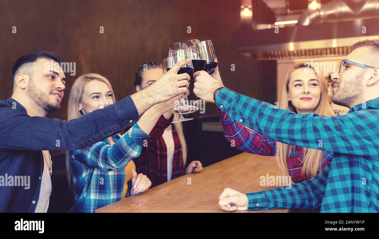 Fröhliche tausendjährige Freunde, die Rotwein in der Kneipe toben und trinken Stockfoto