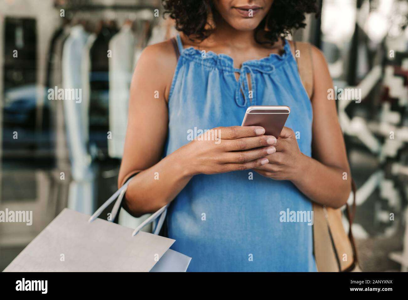 Frau mit der Handy beim Einkauf für die Kleidung Stockfoto