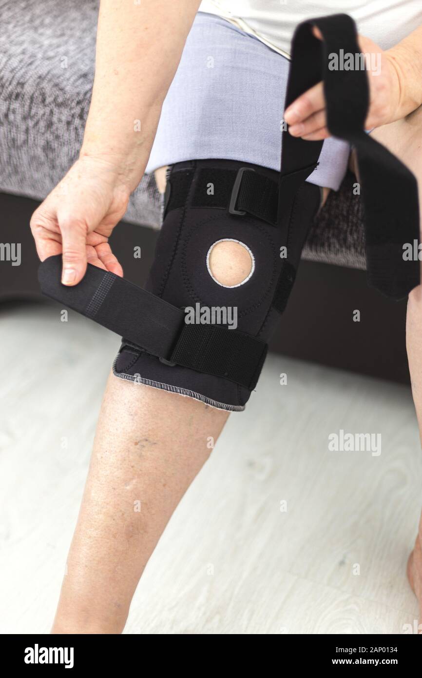 Person, die auf die schützende Knieorthese, Knie Support zu Hause Stockfoto