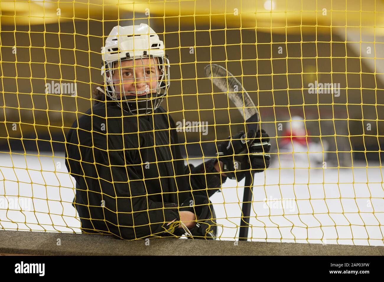 Taille bis Portrait von weiblichen hockey player Lächeln auf die Kamera steht hinter Tor net auf der Eisbahn, kopieren Raum Stockfoto