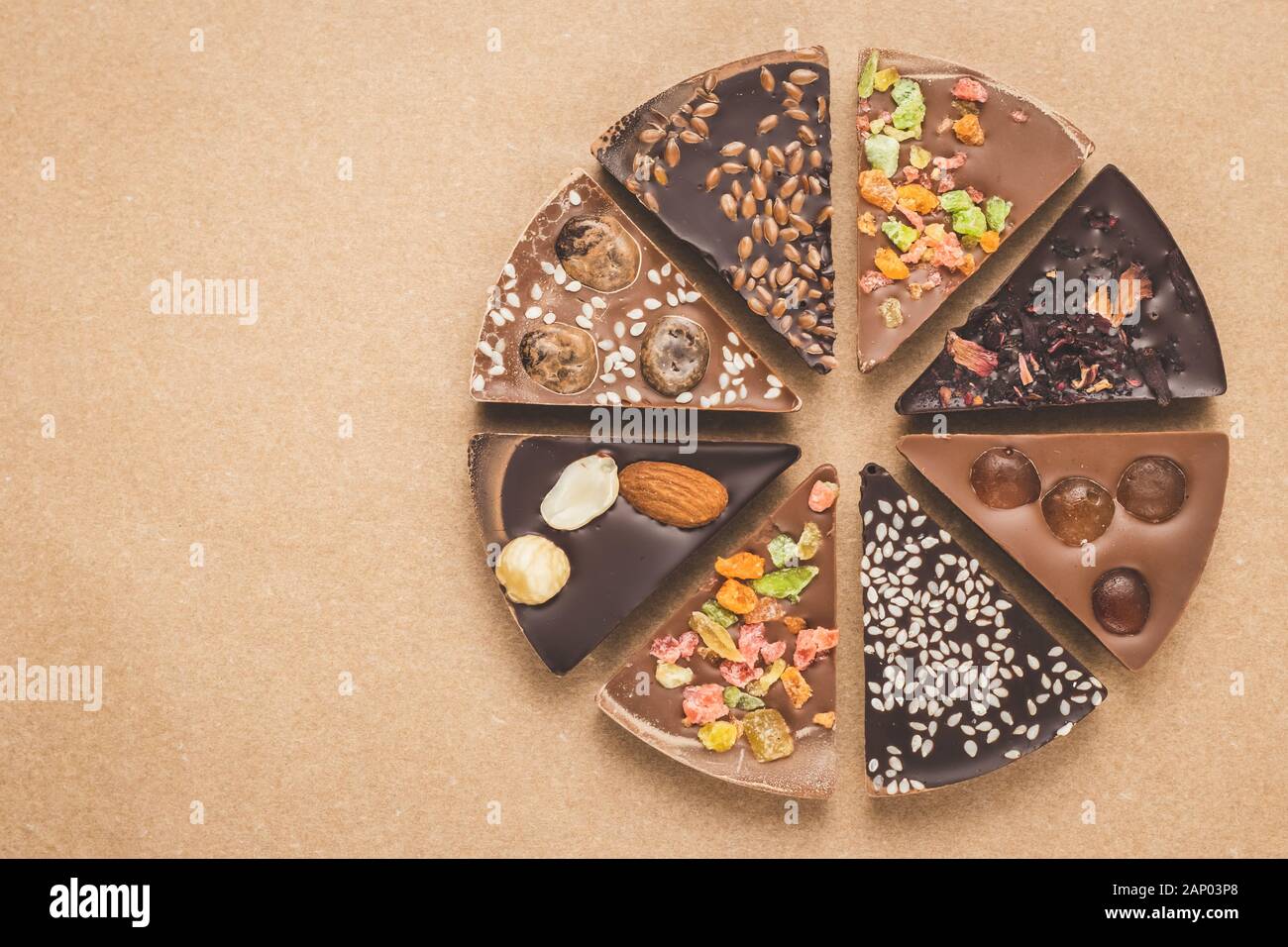 Stücke von Milch und dunkle Schokolade mit Gewürzen auf braunem Hintergrund. Scheiben von Schokolade auf Handwerk Papier, Ansicht von oben. Grußkarte mit kopieren. Homem Stockfoto