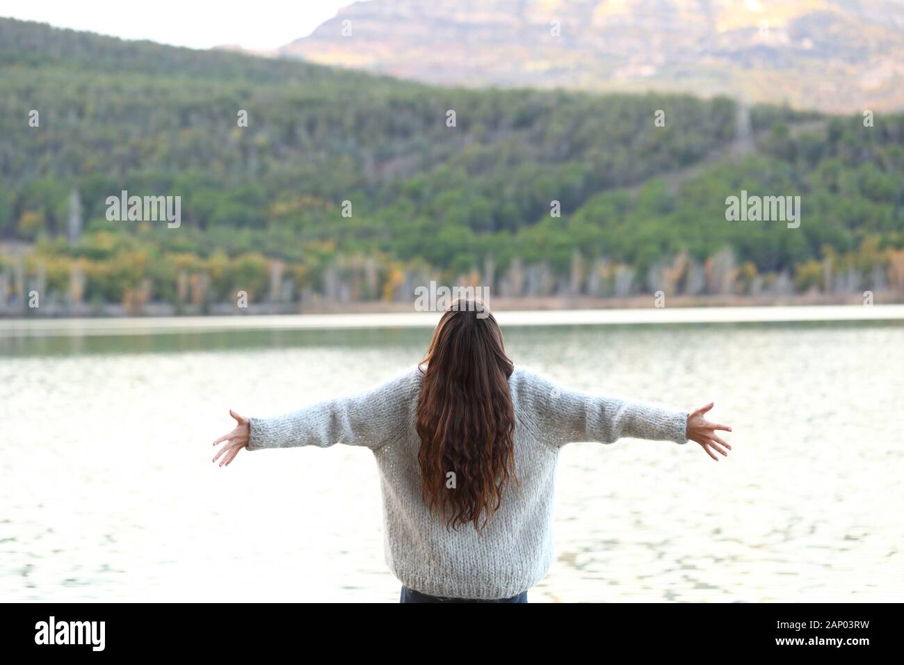 Zurück Blick auf glückliche Frau feiern Feiertage outstretching Arme in einem See Stockfoto