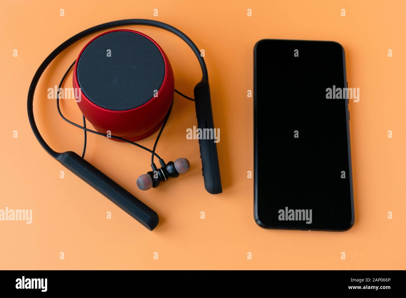 Drahtlose bluetooth-geräte für das Telefon, schwarze Kopfhörer und einen roten Lautsprecher. Headset für Telefon Stockfoto
