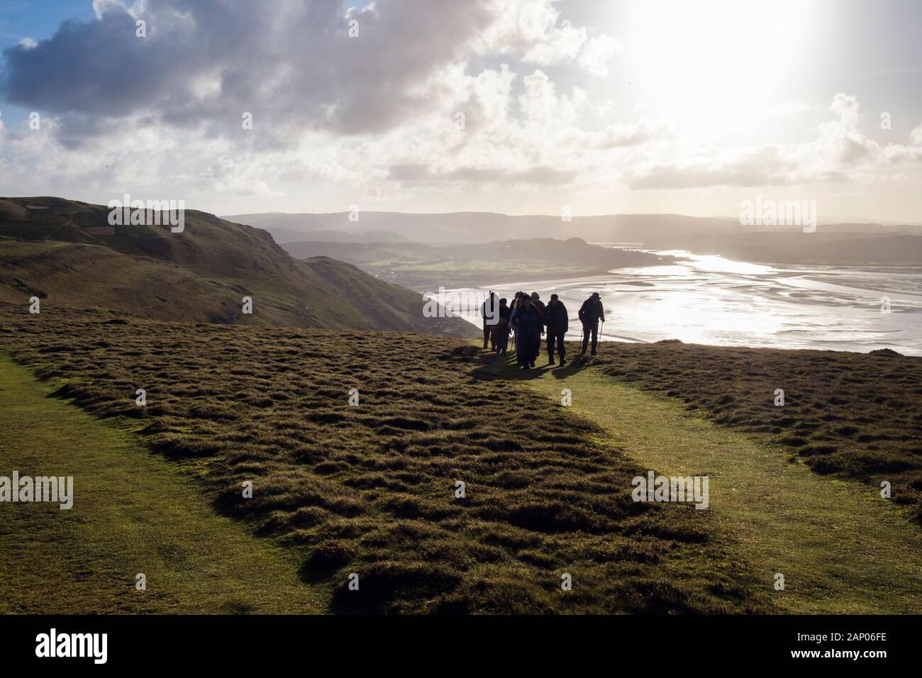 Wanderer wandern die Great Orme Pfad Hintergrundbeleuchtung durch die Wintersonne. Llandudno, Conwy, North Wales, UK, Großbritannien Stockfoto